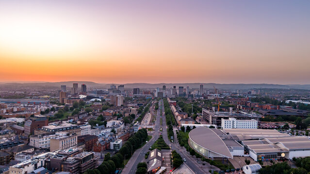 Aerial view looking down Lloyd George Avenue toward the Cardiff city centre skyline at sunset.