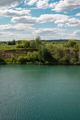 Fototapeta premium Turquoise Lake and Green Shore Under Dramatic Summer Clouds