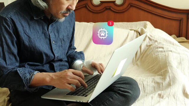 An injured mature Asian man with a hurt hand using a laptop in bed, with a 3D tracked pet paw print smart microchip hardware notification pop up and red counter.