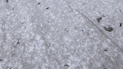 Fototapeta premium Monochrome close-up of pale dusty floor surface with fine debris, subtle track marks, and minimal rough texture.