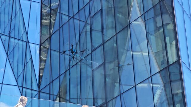 drone cleaning glass facade of modern highrise building