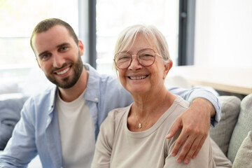 Fototapeta premium Smiling Grandmother and Adult Grandson Embracing in Bright Living Room Family Moment