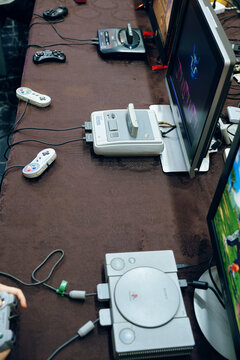 Top view of retro gaming station featuring multiple classic home consoles and wired controllers arranged on cloth-covered table. Bishkek, Kyrgyzstan - April 27, 2025