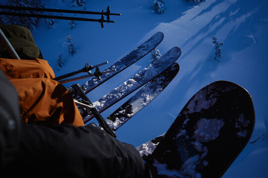 Skiers ride chairlift above snow-covered slopes in winter