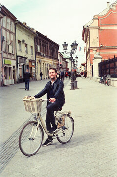 Person Rides Bicycle on Street in Town Center During Day