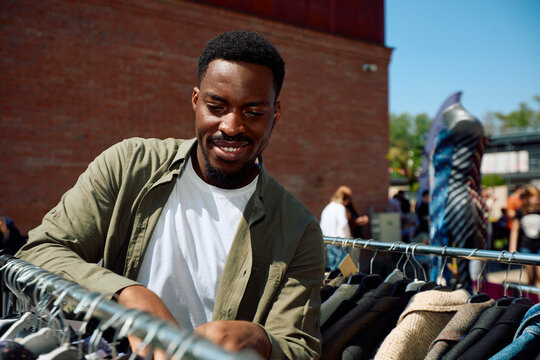 Man Shopping for Clothes at Outdoor Market on Sunny Day in Spring