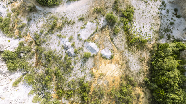 Aerial view of Kamnolom Plese pri Skofljici quarry featuring rocky terrain, gravel piles, and surrounding green vegetation in Mali Vrh pri Smarju, Grosuplje, Slovenia.