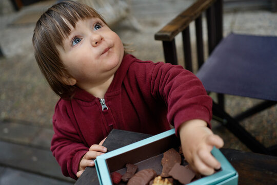 Child Enjoys Chocolate Treats at Outdoor Table in a Busy Area