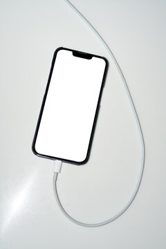 Smartphone with white blank screen charging on table