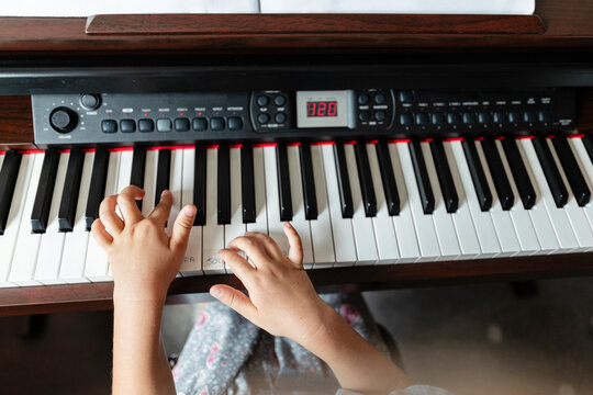 Child hands playing digital piano keyboard during music lesson