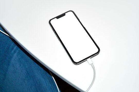 Smartphone with white blank screen charging on table