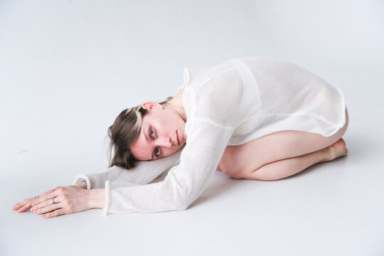 Model in White Outfit Poses on Floor in Studio Setting