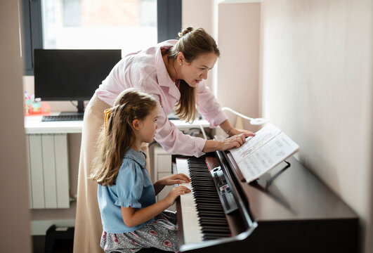 Girl learning to play piano with female teacher