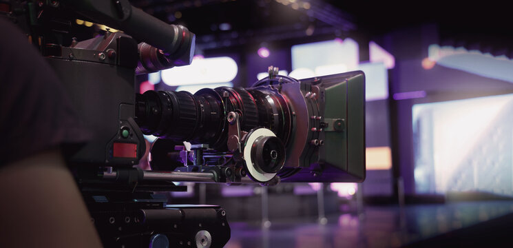 Behind the scenes of movie shooting or video production at studio with high quality camera gimbal or tripod equipment set up and professional film crew team or camera operator with flare lighting.