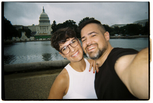 Happy couple taking selfie at US Capitol reflecting pool