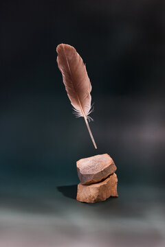 Feather Suspended Above Rocks