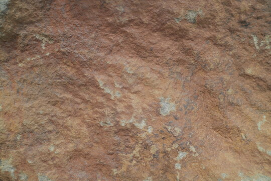Rough orange brown jagged rock surface texture suitable for backgrounds, patterns, or textures in design projects with a natural hard stone theme.