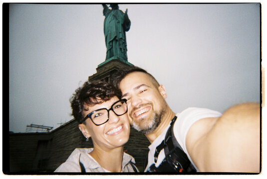 Happy couple taking selfie in front of Statue of Liberty