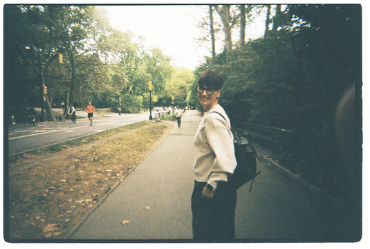 Woman with glasses smiling walking on a path in a large urban park