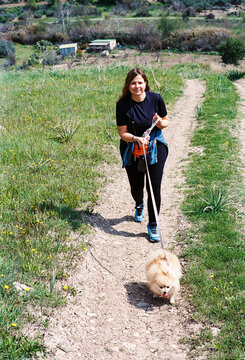 Person Walks Dog on Trail in Rural Area During Daylight Hours
