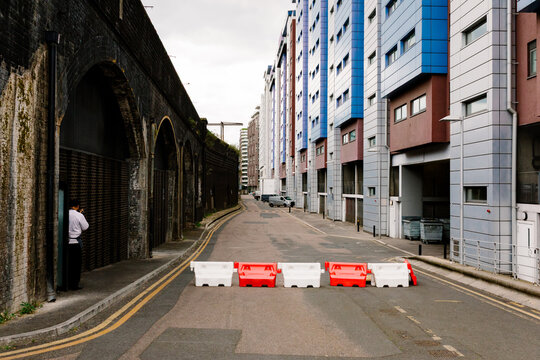 London street blocked by barriers, between brick arches and flats