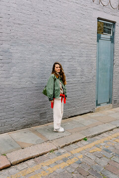 Tourist cheerfully posing in front of a gray brick wall in London