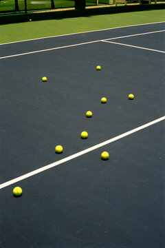 Tennis court with several balls scattered on the ground
