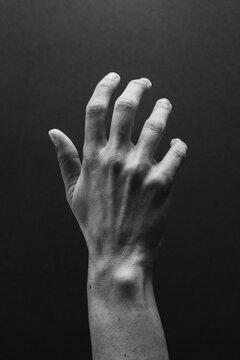 Hand reaching towards the sky with a dark background 