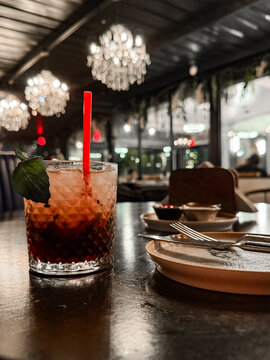 Cocktail on Restaurant Table with Elegant Chandeliers and Moody Light