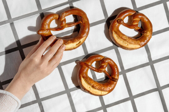 Hand Reaching for Pretzels on a Chackered White Tablecloth