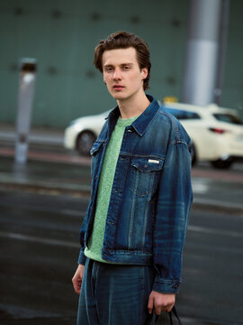 Young Man Wearing Denim Jacket Stands on Street During Day