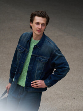 Man in Denim Jacket Stands With Hand on Hip in Modern Space