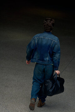 Man Walks With a Bag in a Dark Space During the Day