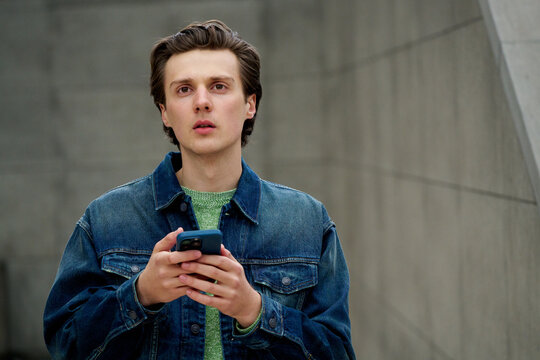 Young Man Using Smartphone in Urban Setting During Day