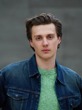 Young Man Poses in Denim Jacket at Urban Location During Daylight