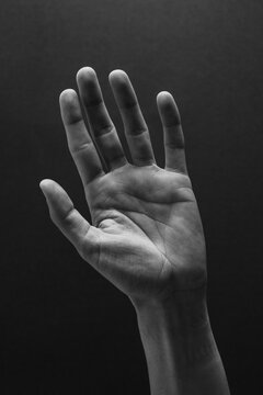 Hand raised against a dark background showing 