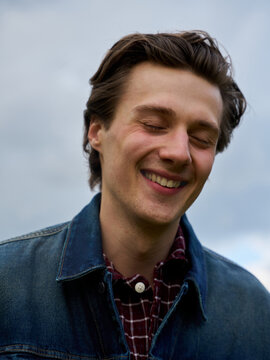 Man Smiling Outdoors During a Cloudy Day in a Park