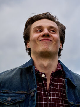 Man Smiles While Standing in an Open Field Under Gray Sky
