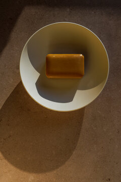 A bar of honey soap on a porcelain bowl 