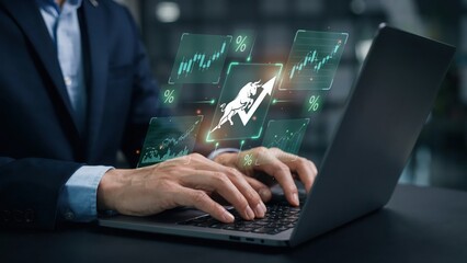 Fototapeta premium Businessman using laptop with rising bull market graph and financial data charts