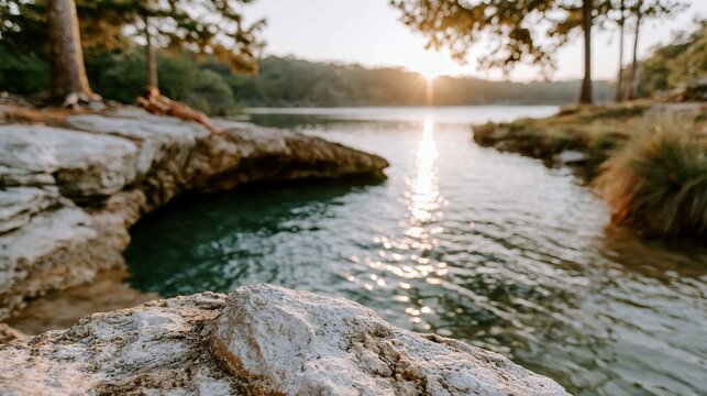 This image captures a tranquil sunset reflecting on the water, framed by rocky shorelines and lush greenery, evoking peace and natural beauty in the surroundings.