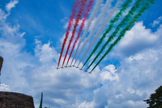 Italy , Aerobatic jet team performing precision formation flight. High-speed military aircraft trailing colored smoke during airshow demonstration.