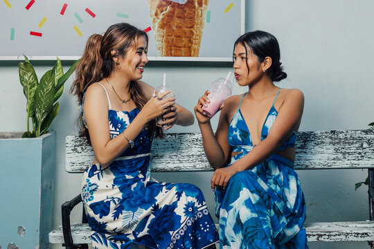 Pareja de amigas compartiendo un momento alegre con bebidas refrescantes durante un d&iacute;a soleado.