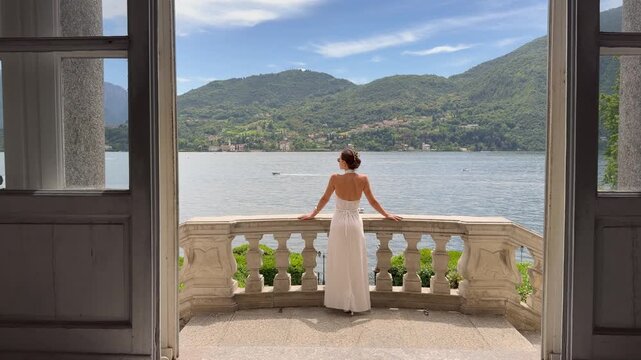 Beautiful Elegant Woman in Backless White Halter Dress on the Curved Baroque Terrace of a Historic Italian Villa With a Breathtaking Panoramic View of Lake Como and Alpine Mountains, Lombardy Italy