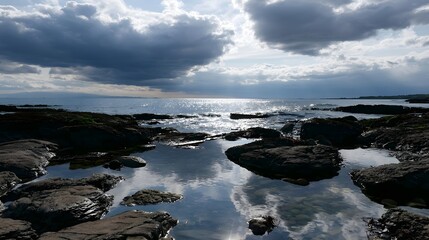 Fototapeta premium Glistening and stormy tide pools reflect the sky with shimmering water along a distant horizon
