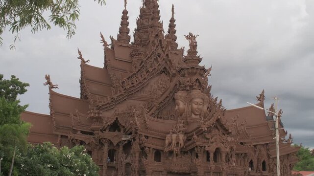 ornate wooden spires and carved faces of the sanctuary of truth in pattaya, showcasing traditional craftsmanship and spiritual symbolism under an overcast sky