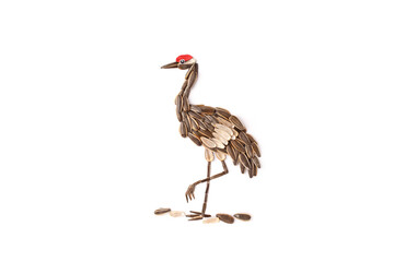 Obraz premium Crane bird made from sunflower seeds with red crown standing on white background. Seed art composition isolated on white background. Nature, wildlife and food creativity concept. Design for poster, 