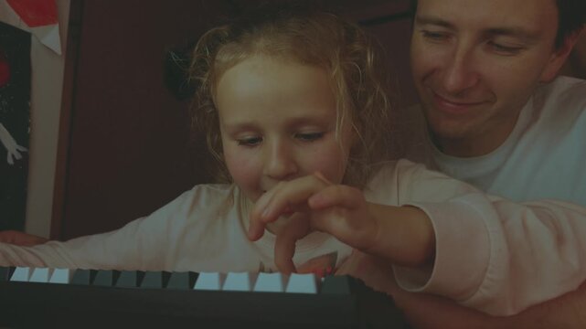 The child writes on the keyboard, the child presses the keyboard, the child and his dad are at the computer