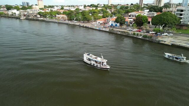 Traditional tourist boats cruising the Tapajos river near the waterfront of Santarem city, Para, Brazil. Aerial drone view of amazon river tourism.