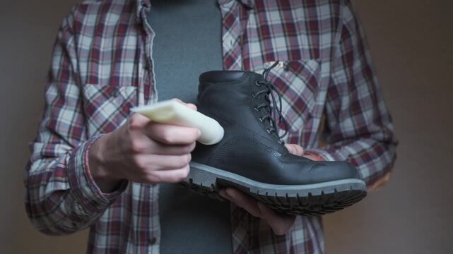 Applying conditioner to a leather boot, the person focuses on cleaning and preserving the material. The scene reflects practical shoe care and restoration.